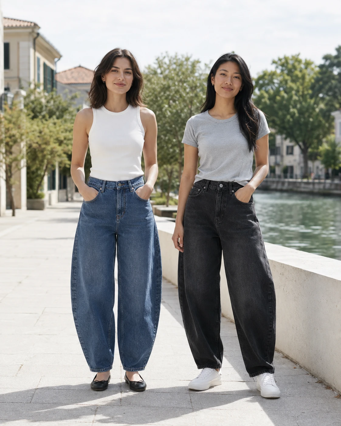 Two women keeping barrel-leg jeans central with minimal tops on a bright canal-side walkway